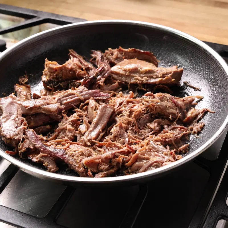 Shredded smoked brisket heating in a pan
